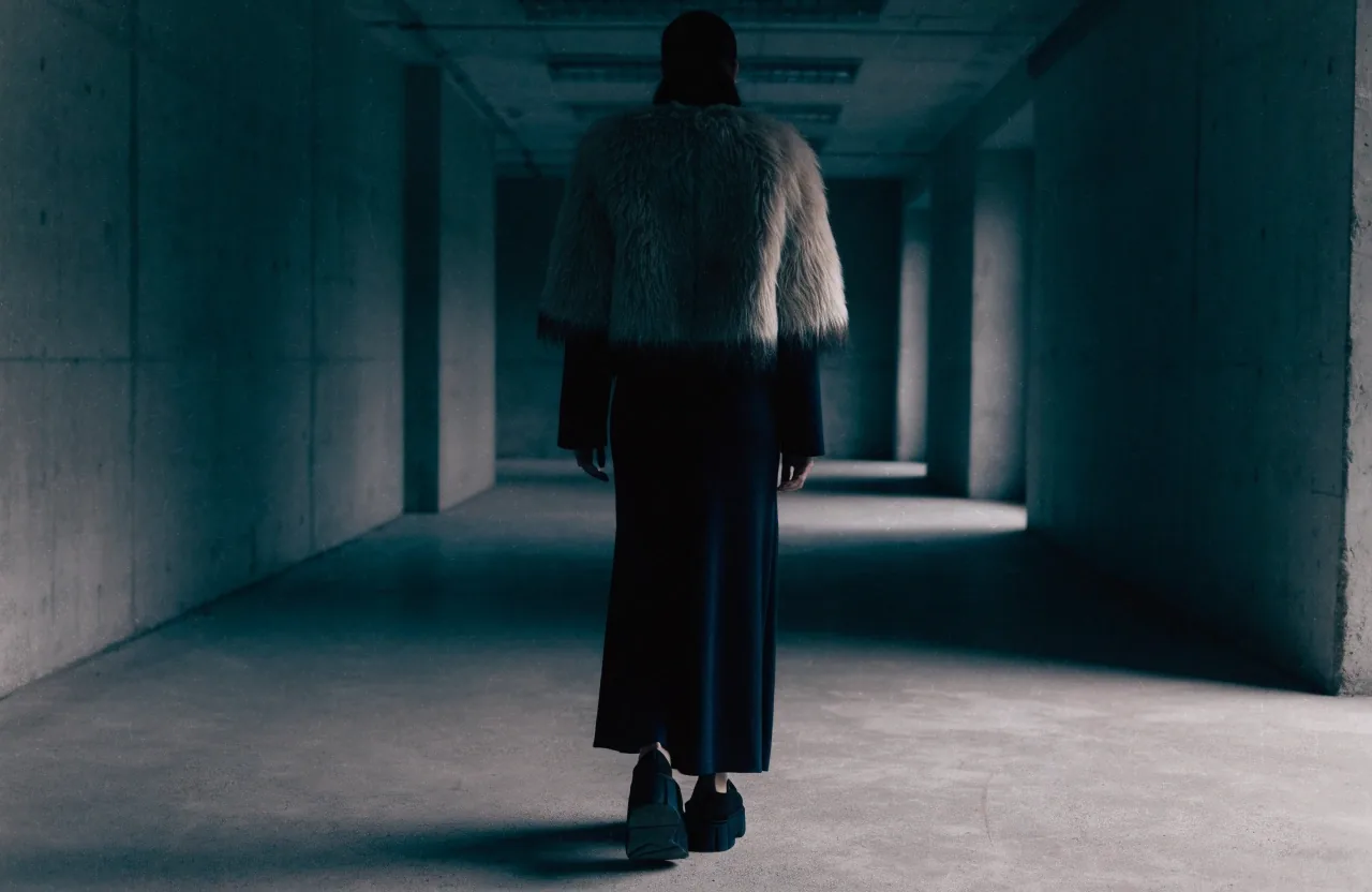 A close profile of a structured shoulder line on a wool jacket against a plain wall